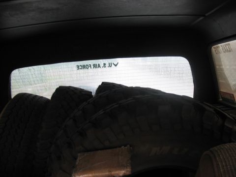 1988 Ford Bronco - Tires are stacked inside a vehicle, with a U.S. Air Force sticker visible on the rear window.