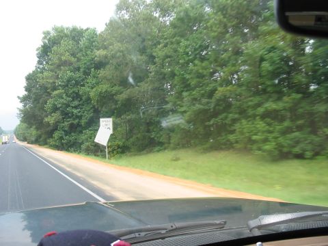1988 Ford Bronco - View from inside a vehicle on a highway, showing trees and a speed limit sign by the roadside.