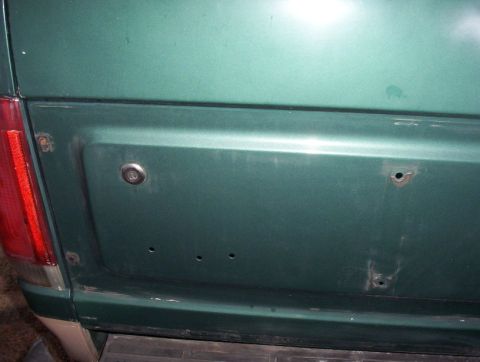 1989 Ford Bronco - Close-up of a green SUV's rear panel, showing a keyhole and mounting holes.