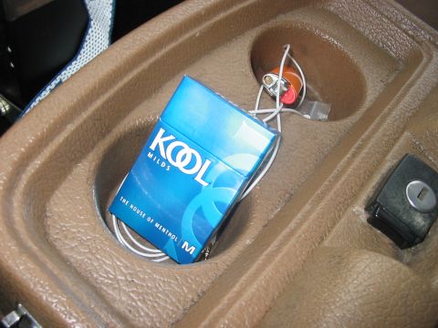 1988 Ford Bronco - A pack of KOOL MILDS cigarettes and a lighter rest in the center console of a vehicle.