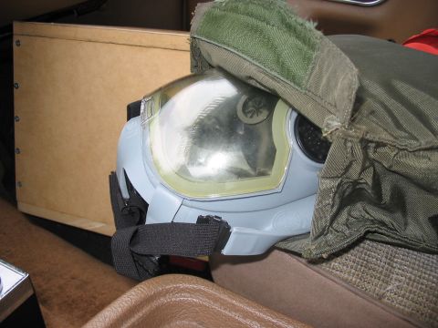 1988 Ford Bronco - A gas mask is partially covered by a green fabric, situated within a vehicle's interior.