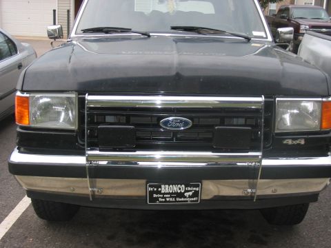 1988 Ford Bronco - Front view of a black 1988 Ford Bronco, its iconic grille and a decorative license plate.