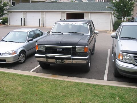 1988 Ford Bronco - A black Ford Bronco is parked in a lot next to a Honda Civic and a Ford F-150.