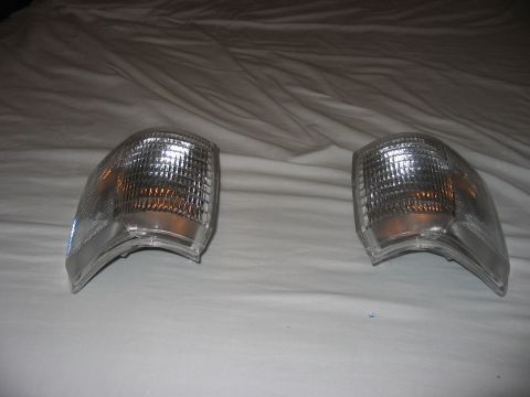 1988 Ford Bronco - A pair of clear turn signal lights with amber bulbs are displayed on a white fabric background.