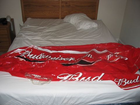 1988 Ford Bronco - Inflatable Budweiser branding is laid out on a bed, with a glass dish in front of it.