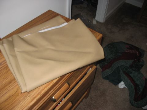 1988 Ford Bronco - Tan fabric is folded on top of a wooden dresser. A pile of blankets is on the floor nearby.
