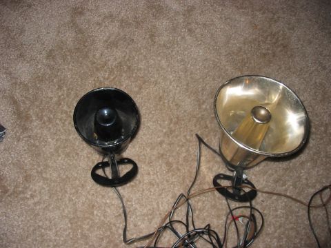 1988 Ford Bronco - Two speakers, one black and one chrome, lie on a carpeted surface with a mess of wires connecting them.