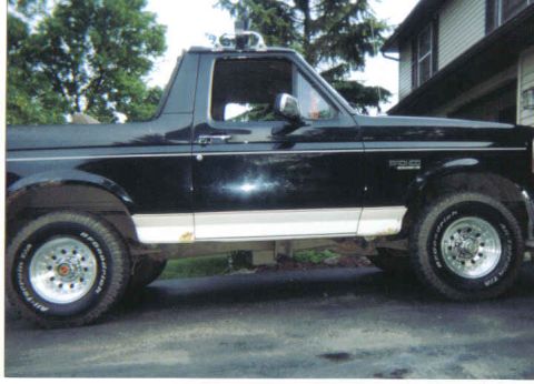 1993 Ford Bronco - This 1993 Ford Bronco is shown from the side, its distinctive black paint with white lower trim and aftermarket wheels.