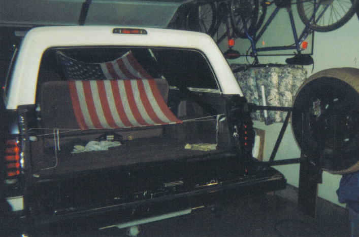 Rear of white Ford Bronco in garage with American flag over rear seat, top open