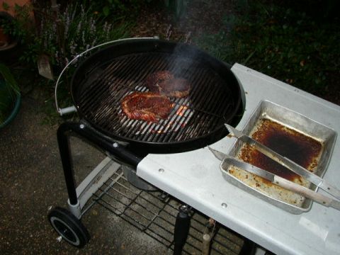 1995 Ford Bronco - Steaks are grilled outdoors next to a pan with tongs and a website logo.