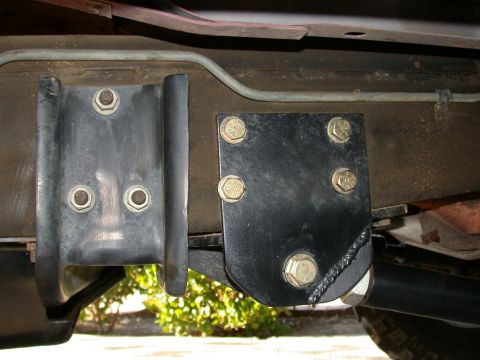 1996 Ford Bronco - Close-up from underneath a truck showing a black bolt-on radius-arm bracket sandwiched to the frame rail with five yellow-zinc grade-marked…