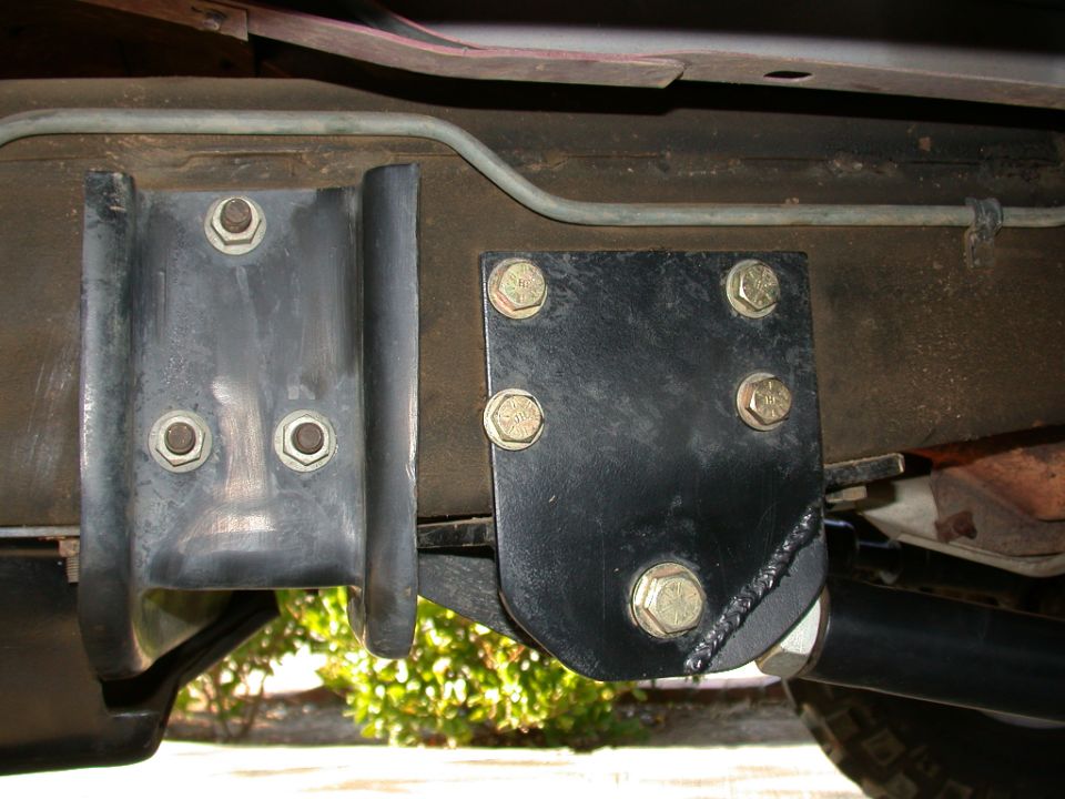 Bolt-on black radius arm bracket clamped to a truck frame rail with yellow zinc bolts
