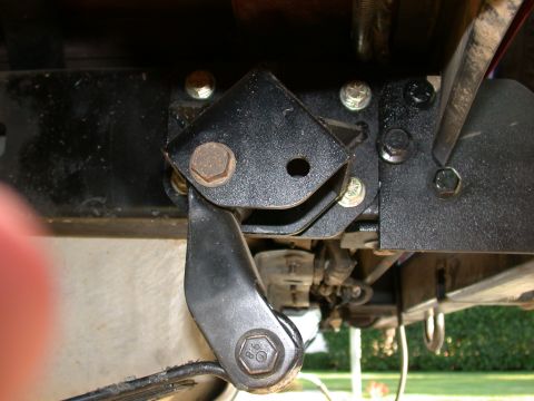 1996 Ford Bronco - Close-up of a black powder-coated suspension bracket bolted to the frame rail underneath a truck, with a heavy hex bolt through the pivot a…