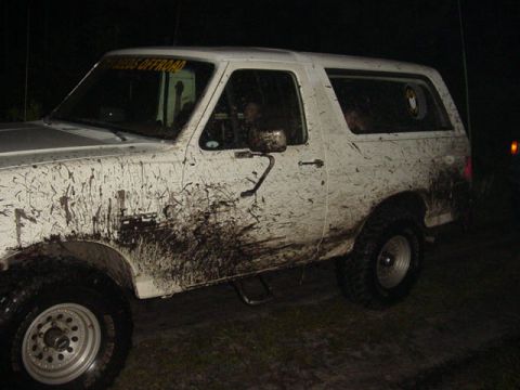 1989 Ford Bronco - This white Ford Bronco is heavily covered in mud, indicating off-road use.