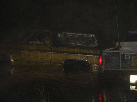 1989 Ford Bronco - A side view of a muddy pickup truck and trailer, captured in low light conditions.