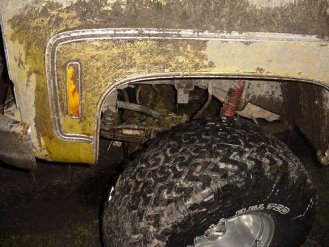 1989 Ford Bronco - Close-up of a muddy vehicle's fender and tire, showing off-road tread.