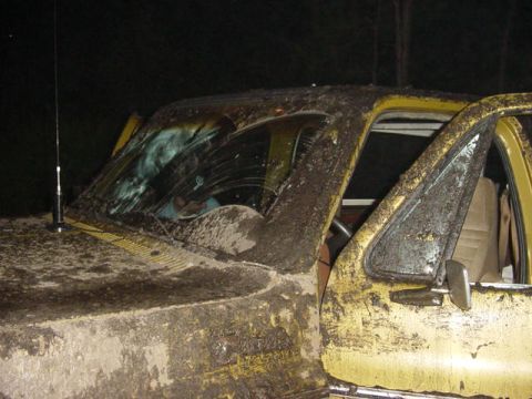 1989 Ford Bronco - This heavily muddied vehicle appears to be a truck, possibly an older model, with its driver's side door ajar.