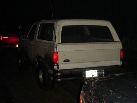 1989 Ford Bronco - A white SUV is parked at night, with another vehicle partially visible in the foreground.