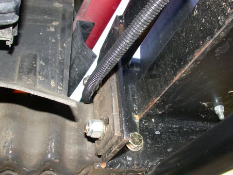 1996 Ford Bronco - Close-up underside view of black vehicle framework and mounting brackets, showing a fresh silver hex nut and threaded stud, plus a flexible…