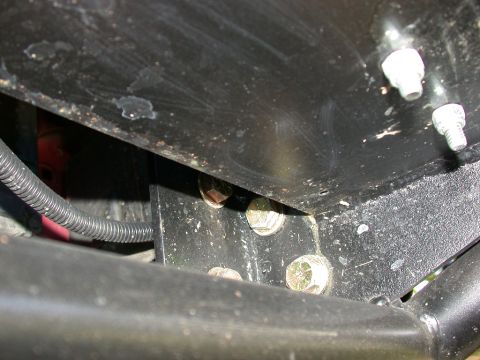 1996 Ford Bronco - Tight underside detail of a black-painted steel bracket or skid plate bolted to a frame crossmember with new zinc-plated hex bolts and expo…