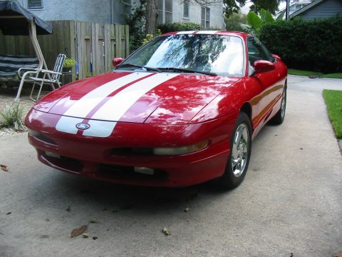 1997 Ford Probe - A red 1997 Ford Probe is parked in a driveway, prominent white racing stripes.