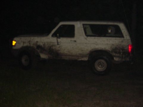 1989 Ford Bronco - Side view of a white Ford Bronco, heavily soiled with mud, seen in darkness.