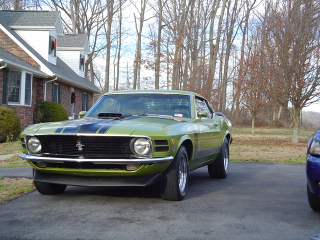 Green 1970 Ford Mustang with black racing stripes parked in driveway