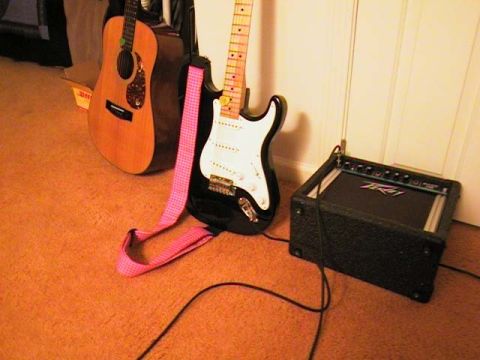 2000 Jeep Liberty - A black electric guitar with a pink strap and an acoustic guitar are positioned near a Peavey amplifier on an orange carpeted floor.