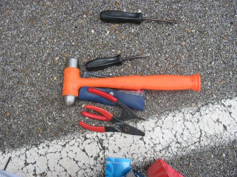 1988 Ford Bronco - Tools including an orange mallet, pliers, and screwdrivers are arranged on a gravelly surface with a white line.