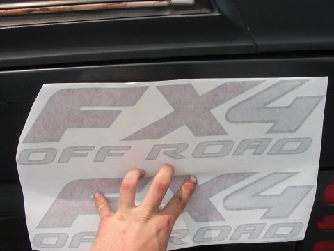 1988 Ford Bronco - A person is holding a sheet of FX4 Off Road decals, ready to apply them to a vehicle.