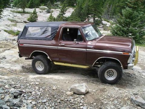 1996 Ford Bronco - This 1978 Ford Bronco is equipped with off-road tires and a brush guard, navigating a , wooded landscape.