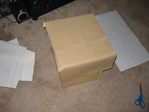 1988 Ford Bronco - A speaker box is covered in brown paper, with white paper and a pair of scissors nearby on the carpet.
