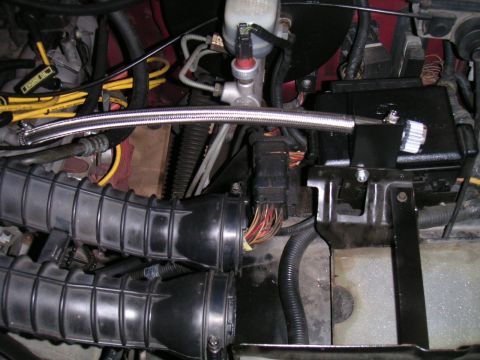 1994 Ford Bronco - Overhead engine bay view showing two large black corrugated intake ducts, a braided stainless-steel hose routed across the bay, yellow spar…