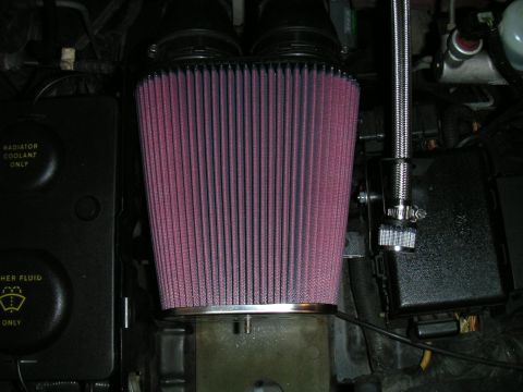 1994 Ford Bronco - Head-on view of a large pink pleated K&N-style conical air filter on a chrome base, mounted in an engine bay above a bare aluminum casting…