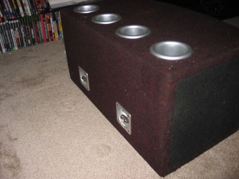 1988 Ford Bronco - Custom speaker box with four cup holders and two input jacks, seen on carpet with a shelf of DVDs in the background.