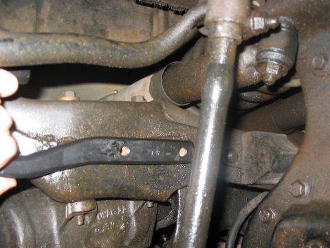 1988 Ford Bronco - Close-up view of greasy vehicle suspension components, with a tie rod end and sway bar link visible.