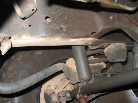 1988 Ford Bronco - Close-up view of the underbody suspension components and a tire, showing rust and wear.