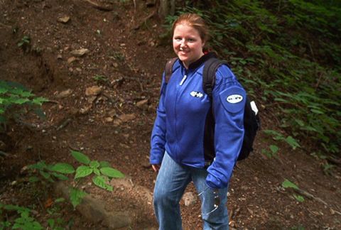 1985 Ford LTD Crown Victoria - A woman smiles while standing on a dirt path surrounded by greenery.