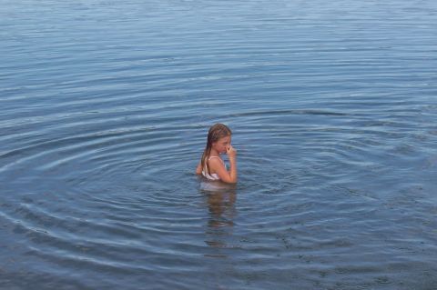 1992 Ford Bronco - A young girl stands in calm water, with ripples spreading around her.