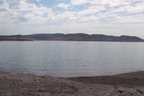 1992 Ford Bronco - A wide view of Lake Pleasant under a cloudy sky, with hills in the background and a buoy in the water.