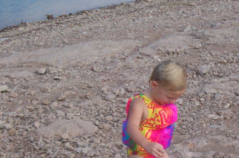 1992 Ford Bronco - Child in a life vest on a rocky beach near the water.