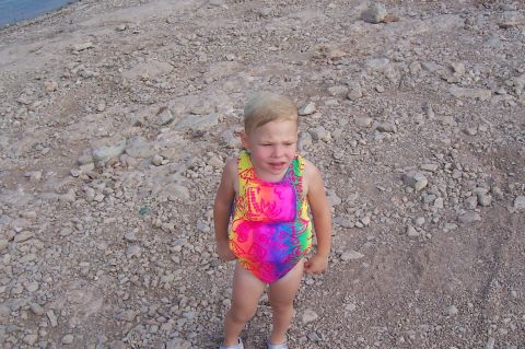 1992 Ford Bronco - A young child stands on a rocky beach, looking upset.