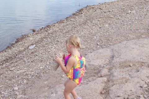 1992 Ford Bronco - Child explores the rocky shore of a lake, holding a large stone.