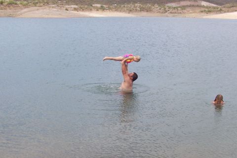 1992 Ford Bronco - A man lifts a child above the water while another child swims in the lake.