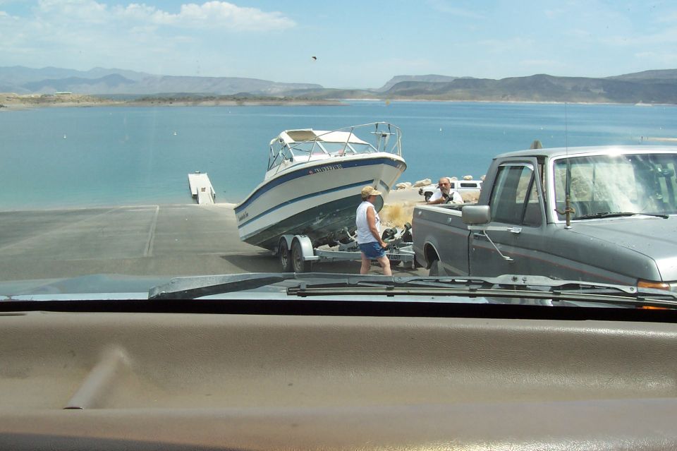 Truck backing a boat on a trailer down a ramp into a lake