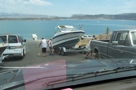 1992 Ford Bronco - People are launching a boat into a lake from a ramp, with a pickup truck and a van present.