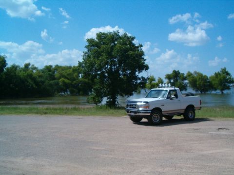1996 Ford Bronco - A white Ford Bronco is parked near a body of water under a partly cloudy sky.
