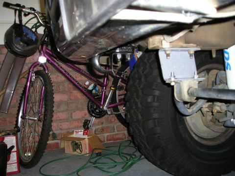 1996 Ford Bronco - A bicycle is parked next to the suspension and tire of a vehicle.