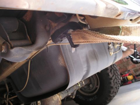 1996 Ford Bronco - This image shows the underbody of a vehicle, focusing on the fuel tank and a strap mechanism.
