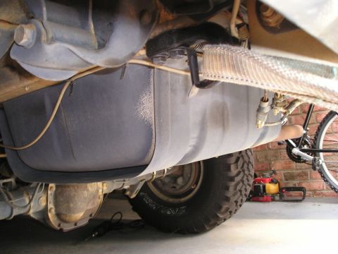 1996 Ford Bronco - Undercarriage view of a vehicle's fuel tank and differential, with a bicycle and chainsaw in the background.